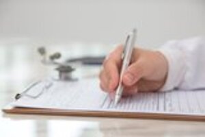 Hand of doctor writing on prescription